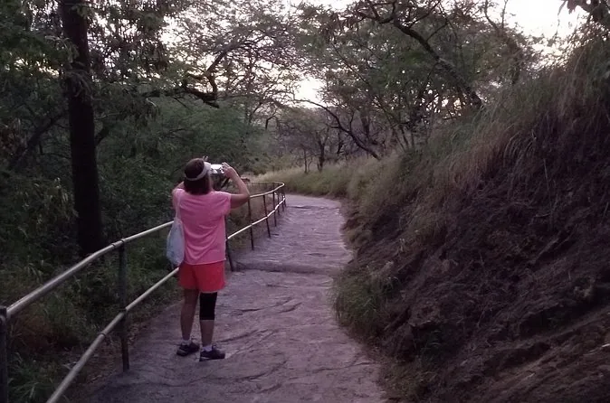 A hiker taking a photo from a railed path on the crater trail